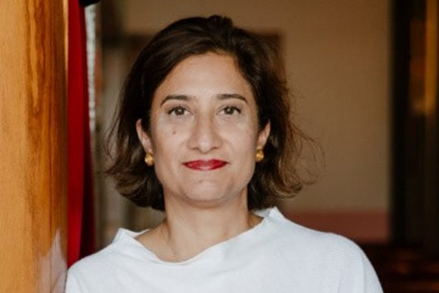 Saba Brelvi- a women with light brown skin, brown short hair, and red lipstick in a white blouse