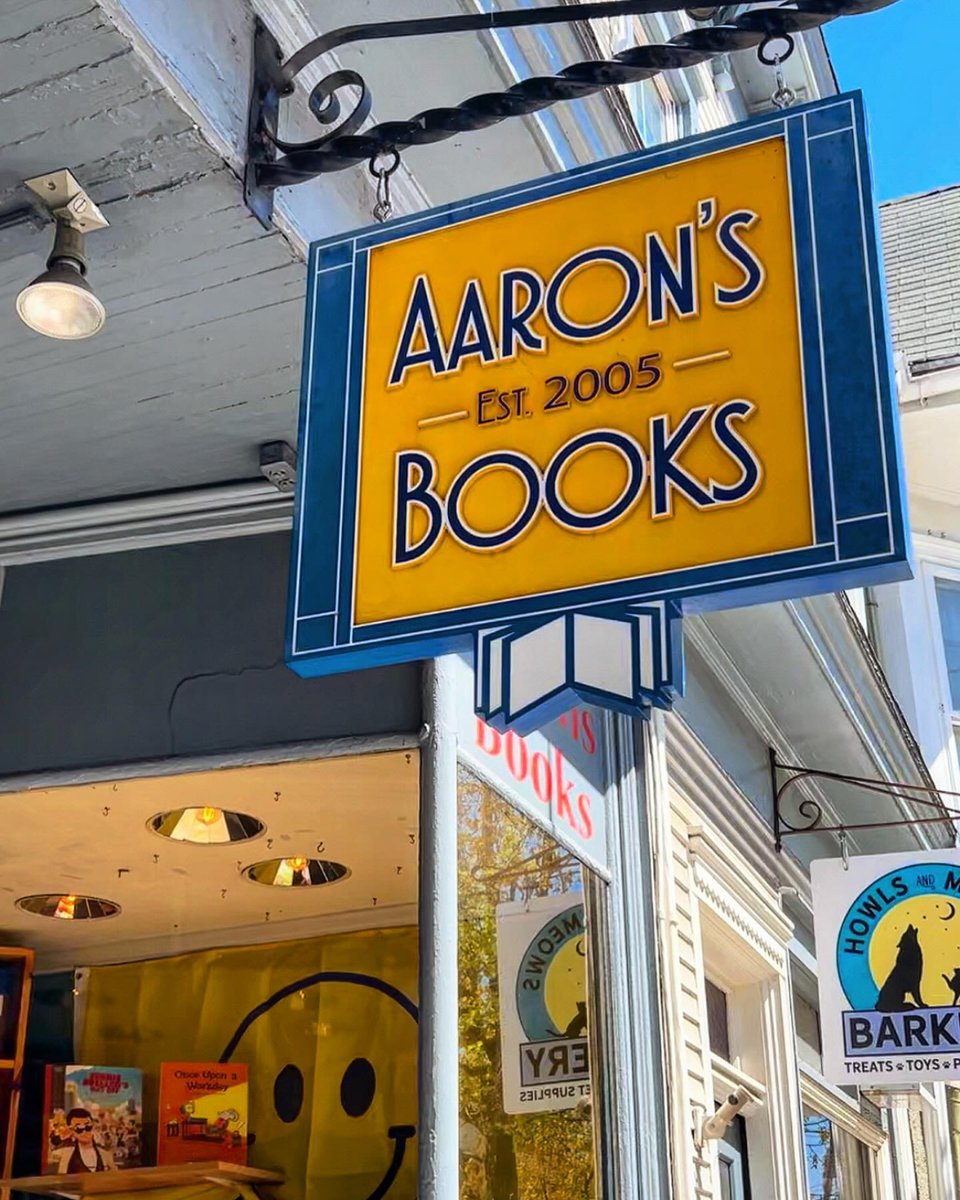 storefront with yellow sign and red, yellow, and orange balloons